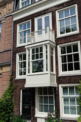 Obraz premium A traditional Dutch townhouse with a distinctive bay window and dormers, flanked by other historical buildings