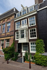 Fototapeta premium A traditional Dutch townhouse with a distinctive bay window and dormers, flanked by other historical buildings