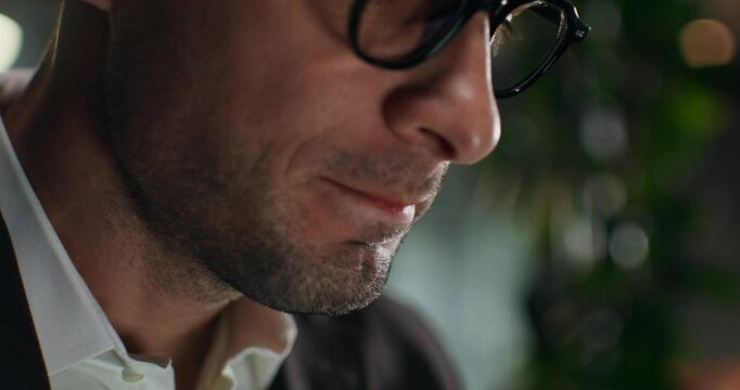 A man drinks coffee while working in the office. Close-up of his face