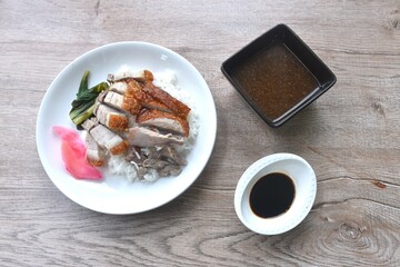slice roasted duck couple crispy pork topping rice with pink pickled ginger and boiled cabbage dressing sweet soy sauce on plate 