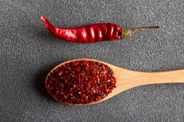 Red pepper flakes.Red chili peppers in wooden spoon on gray background.Dried chili peppers
