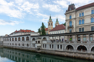 Obraz premium A scenic view captures the architectural beauty along the Ljubljanica River in Ljubljana, Slovenia, showcasing the renowned Central Market colonnade, designed by Jože Plechnik