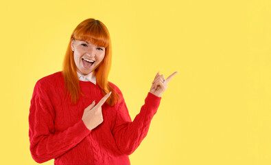 Cheerful young woman in a red sweater gesturing with enthusiasm against a bright yellow background