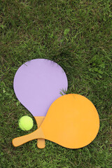 Beach tennis rackets and ball on grass, top view. Active lifestyle, games and sports. Beach tennis...