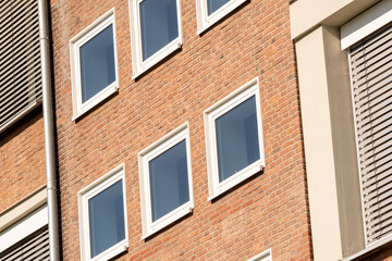 Modern brick building facade featuring white windows and external blinds