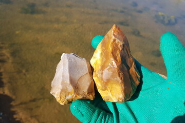 Samples of ordinary slightly colored flints in hand, examination of stones near a pond