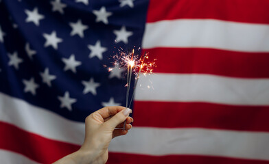 Sparklers in hand on an American Flag background. Independence day United States. Celebration 4th...