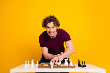 Young man playing chess with a confident expression against a bright yellow background enhancing...