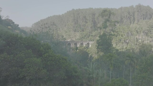 Aerial view of most scenic Nine Arch bridge in mountain jungle of Sri Lanka in Ella. Sunrise illuminates iconic Nine Arch Bridge surrounded by lush greenery. 120 fps ProRes 422 10 bit DJI D-Log video.