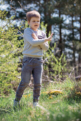 A cheerful, playful boy against a bright summer forest background