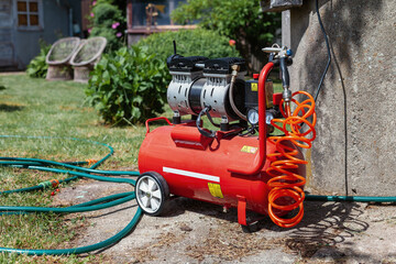 Red air and water compressor in the garden yard by the well