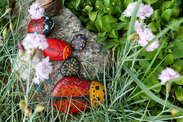 Handmade painted pebbles resemble ladybugs in a simple village flower garden