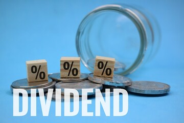 Financial Dividend Concept with Percentage Cube and Coins on Blue Background
