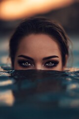 Woman's face submerged in water, sunset