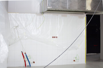 Freshly tiled wall with red and blue pipes on the floor and large pipes