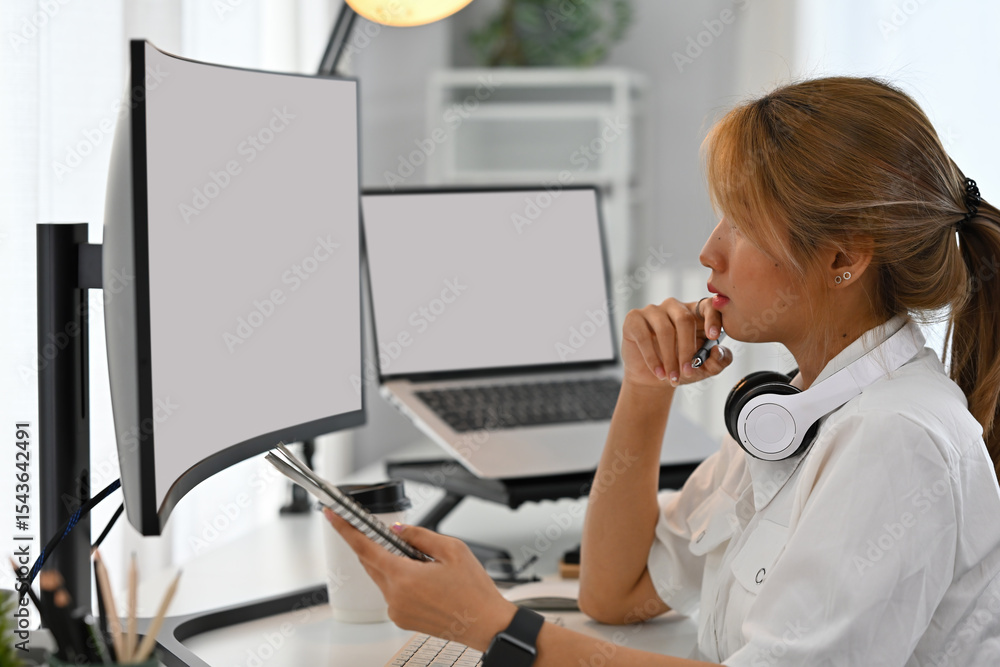Aufkleber young female programmer analyzes code on a dual monitor setup in a modern workspace