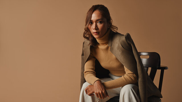 Elegant Style on Neutral Background with Confident Woman in Modern Business Casual Sitting on Chair