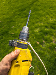 Damaged drill with electrical cord in grassy yard