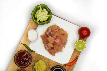 Preparation ingredients ( lime, chilies, onion, garlic, coriander root, galangal and lemon grass) for cooking fresh chickens on wooden cutting board, clipping path on white background.