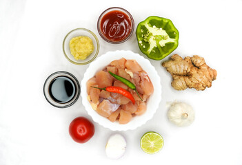 Raw pieces meat ingredients of chicken in a white bowl with spices, herbs, vegetables and sauce on white background. Raw ingredients for goulash or shish kebab.