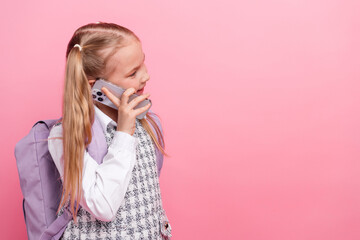 Smiling young schoolgirl talking on smartphone with cheerful expression, wearing uniform and...