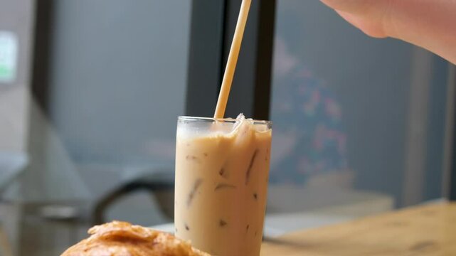girl stirring cappuccino in glass. Milkshake with coffee in beautiful cup. Coffee drink with foam. process of making latte. close-up of female hand with a manicure stirring cappuccino. . High quality
