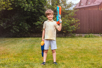 Happy child playing with water gun outdoors on a sunny day. Perfect summer activity, game, fun, and...