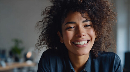 Smiling woman with curly hair in a modern indoor workspace
