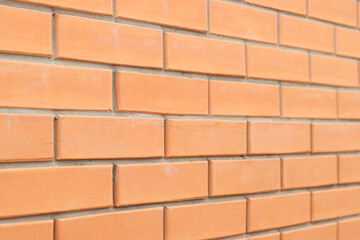 Brick wall background from the side with selective focus. Orange brick background for exterior design. Construction concept. Wall with classic checkerboard pattern and visible joints