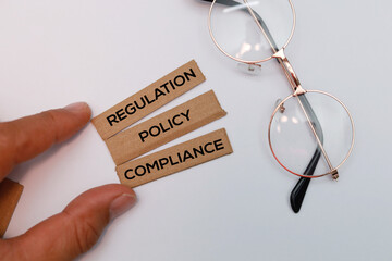 Hand holding a stick with the three words regulation policy and compliance the ethical concept