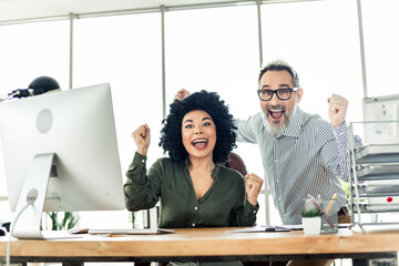 Two excited coworkers celebrating success in a modern office environment, showcasing teamwork and a diverse workplace