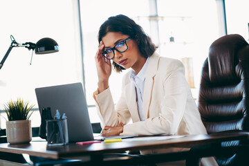 Professional businesswoman wearing formal attire contemplating ideas at her modern office workspace...