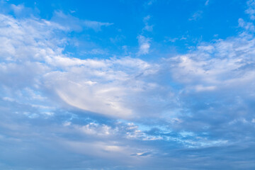 Clouds float gently across a serene blue sky tinted with the soft hues of sunset, creating a tranquil and dreamy evening atmosphere.
