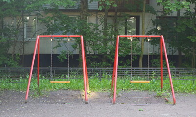 Two children's swings in the courtyard of a residential building