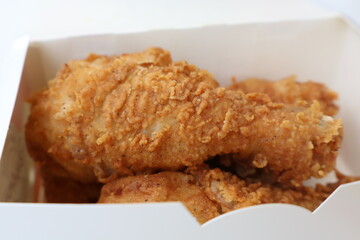 Box of fried chicken with a crispy crust. The chicken is golden brown and looks delicious. The box...