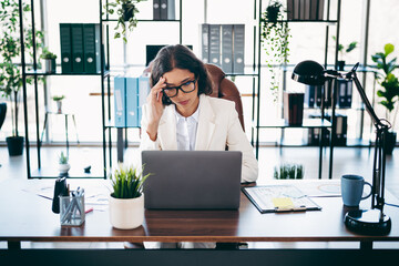 Confident businesswoman working in a modern office, analyzing documents at her desk, showcasing...