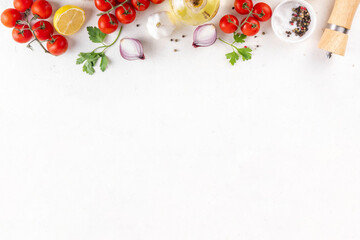 Spices, black pepper, garlic, onion, greens and tomatoes, olive oil on white cooking table. Ingredients for cooking food on the white stone concrete background top view copy space.