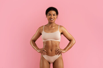 Closeup portrait of smiling African American woman in nude underwear posing confidently on pink...