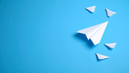 A large paper airplane leads smaller ones on a dotted path across a vibrant blue background