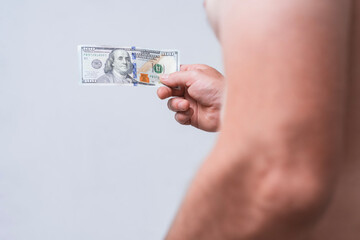 Close-up of a male hand with hundred dollar bill on a bare belly. Conceptual image for themes of...