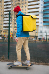 Food delivery man riding a longboard while using a smartphone app, navigating through a residential...