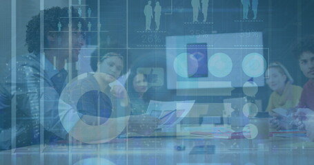 Collaborating business professionals reviewing laptop data in conference room, with printed charts