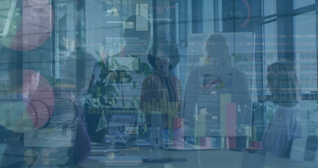 Reviewing data forecasts office team examining charts in conference room, with laptops, flipchart