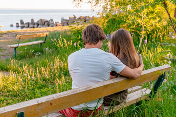 A date between a teenage boy and a girl on the riverbank in summer