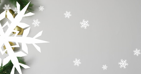 Obraz premium Arranging white snowflake cutout pine branches and golden ornament on gray backdrop, copy space