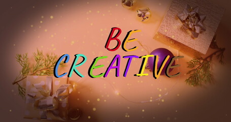 Displaying hand-lettered BE CREATIVE text on tabletop setup, with gift boxes and fairy lights