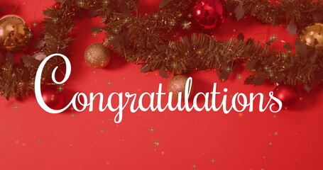 Displaying white cursive 'Congratulations' text on red wall, with green tinsel garland and baubles