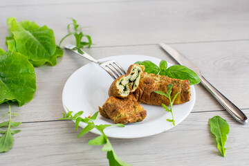 Breakfast of omelette with greens in the form of a roll on a wooden table
