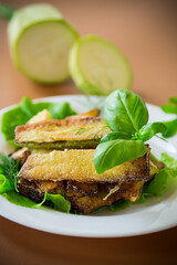 Zucchini with a crispy crust and fresh salad on a brown background