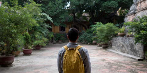 Backpacker with yellow backpack exploring tranquil temple garden